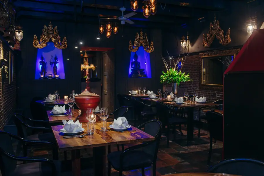 De zaal met blauw verlichte Thaise nissen en rijen gedekte tafels