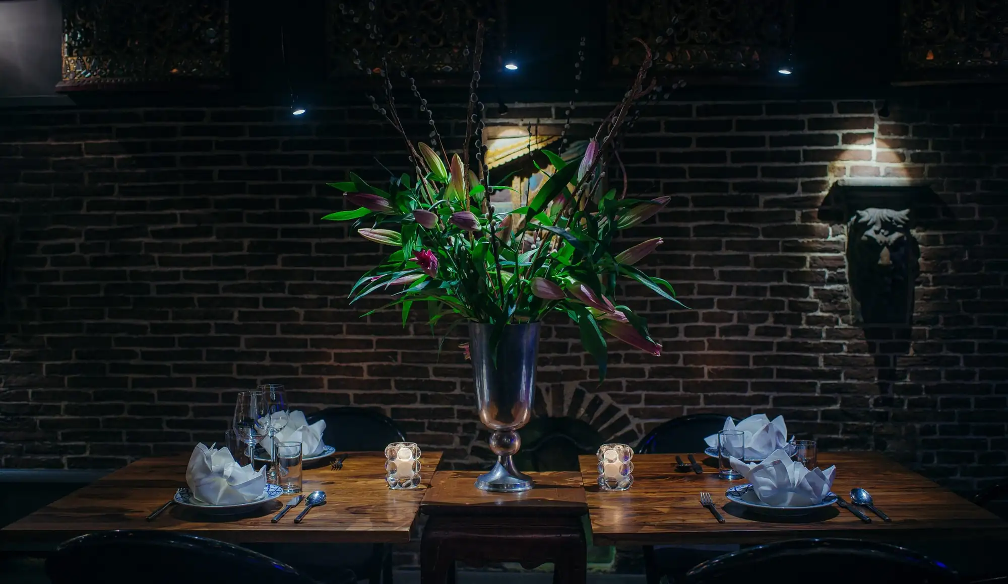 Gedekte tafel met bloemstuk tegen de bakstenen muur in het restaurant
