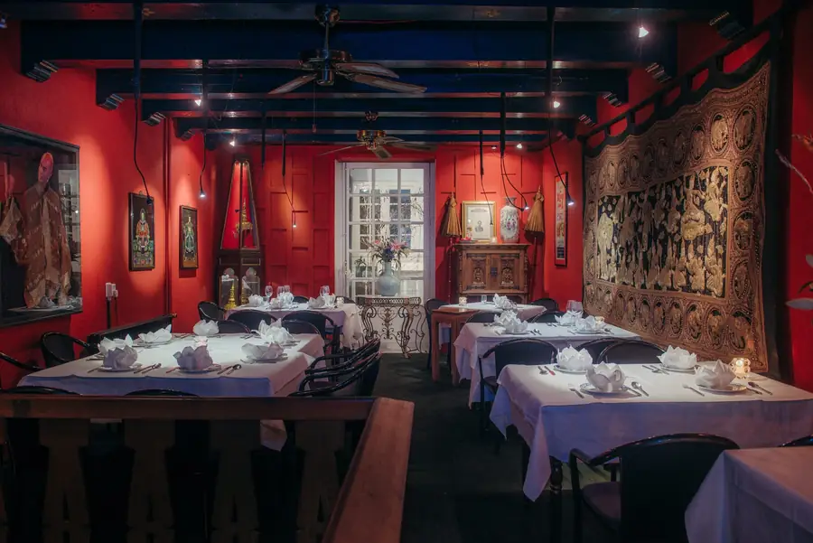 De rode zaal met gedekte tafels, Thaise wandkleden en een raam naar de gracht