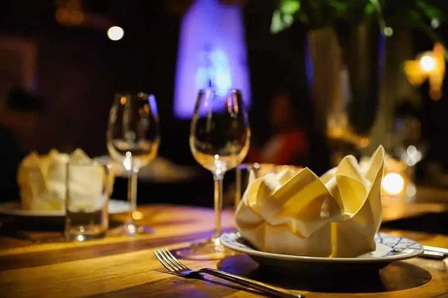 Gedekte tafel met wijnglazen en een gevouwen servet bij kaarslicht