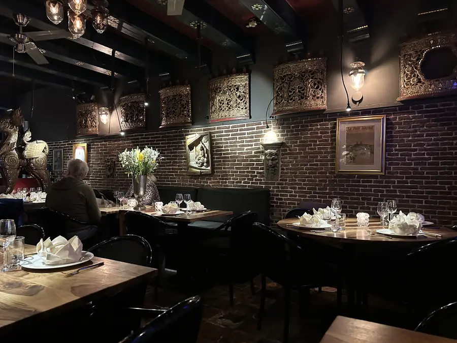 Zaal met bakstenen muur, gedekte tafels en een bloemstuk
